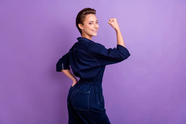 Foto del lado del perfil de la sonriente mujer valiente fuerte fuerte levantar el puño feminismo aislado sobre fondo de color púrpura — Foto de Stock