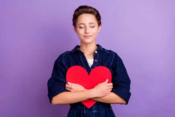 Portrét mladé usmívající se mírumilovné snivé ženy objetí objetí papír srdce Valentýna dárek izolované na fialové barvy pozadí — Stock fotografie