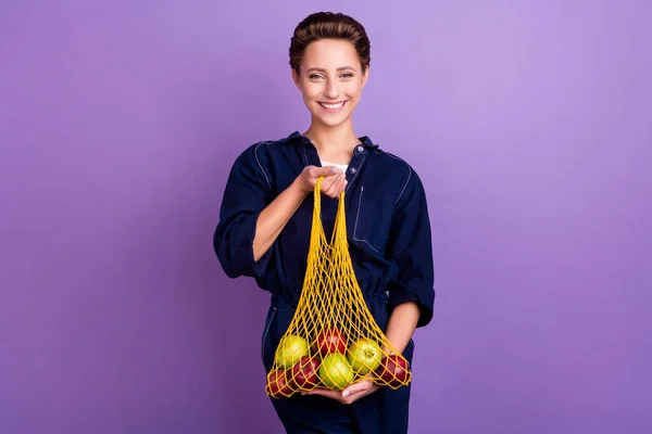 Foto de boa morena milenar senhora segurar maçãs usar jeans em geral isolado no fundo cor violeta — Fotografia de Stock