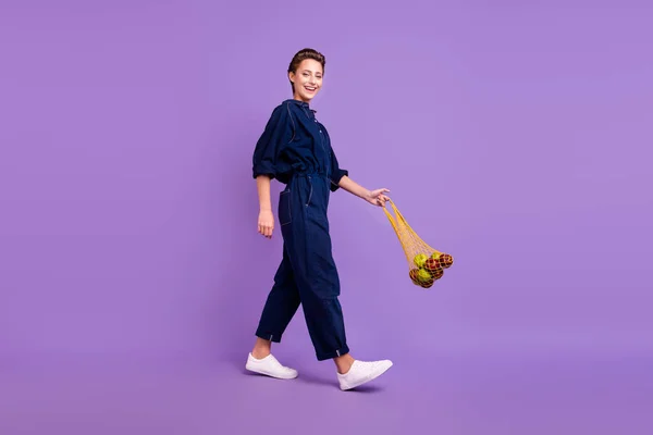フルサイズプロフィール側の写真の若い笑顔の女の子は買い物に行くとともに再利用可能なメッシュバッグ購入リンゴ隔離された紫色の背景 — ストック写真