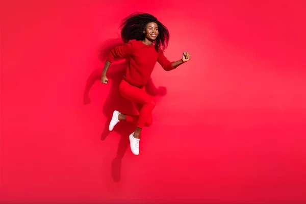 Teljes méretű profil oldalán fotó a fiatal afrikai lány boldog pozitív mosoly megy séta fuss fuss ugrás elszigetelt piros szín háttér — Stock Fotó
