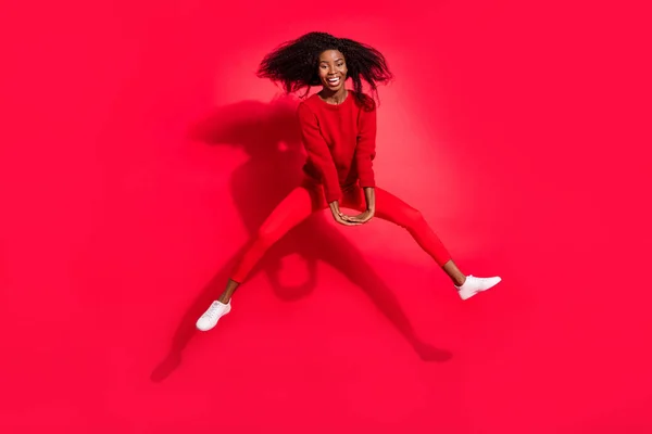 Полная длина фото молодой черной девушки счастливая положительная улыбка весело прыгать изолированы на красный цвет фона — стоковое фото