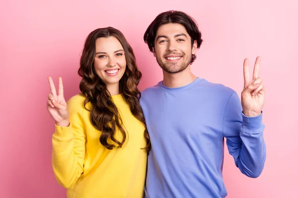 Fénykép a fiatal vidám pár boldog pozitív mosoly mutatják győzelem v-jel elszigetelt rózsaszín szín háttér — Stock Fotó