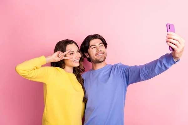 若いカップルの写真幸せな正の笑顔撮影自撮りスマートフォン女の子ショークールなvサイン隔離されたピンク色の背景 — ストック写真