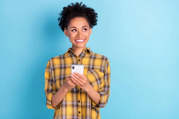 Foto retrato rizado mujer sonriendo usando el teléfono móvil mirando copyspace aislado pastel color azul fondo — Foto de Stock