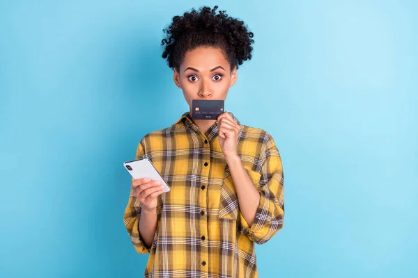 Foto retrato encaracolado mulher usando celular coberto boca com cartão de crédito banco isolado pastel azul cor fundo — Fotografia de Stock