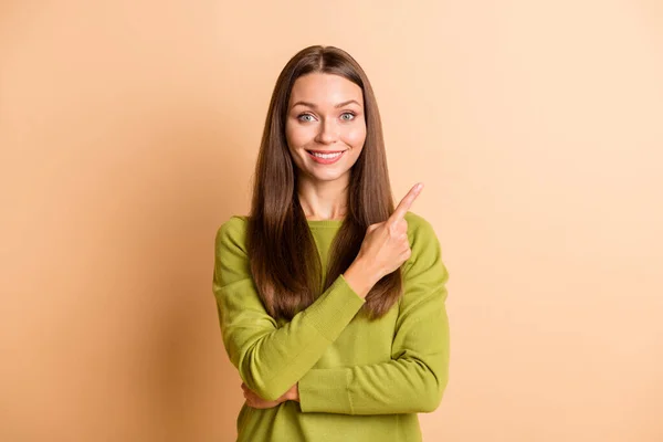 Fotografie veselé pozitivní dáma přímý prst prázdný prostor nosit zelený svetr izolované béžové barvy pozadí — Stock fotografie
