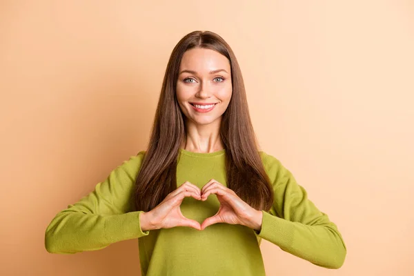 Zdjęcie romantycznej dziewczyny wykazać kształt serca palce nosić zielony sweter odizolowany beżowy kolor tła — Zdjęcie stockowe