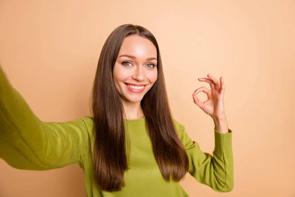 Auto-retrato de agradável linda menina alegre de cabelos longos mostrando anúncio ok-sinal isolado sobre fundo de cor pastel bege — Fotografia de Stock