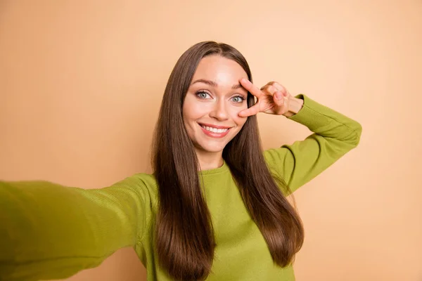 Autoritratto di affascinante allegra ragazza dai capelli lunghi che mostra v-segno vicino occhio divertirsi isolato su sfondo di colore pastello beige — Foto Stock