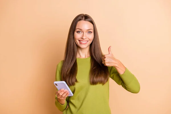 Çekici, neşeli kızın portresi. Bej renkli arka planda izole edilmiş parmak ucu reklamını gösteren bir cihaz kullanıyor. — Stok fotoğraf