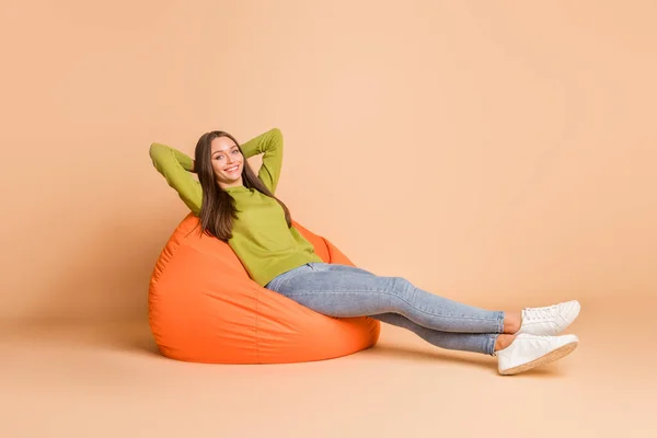Full length body size view of nice pretty cheerful girl lying in orange bag chair resting isolated over beige pastel color background — Stock Photo, Image