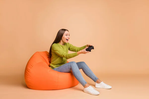 Profil zdjęcie dziewczyny siedzieć beanbag trzymać gamepad grać w gry nosić zielone trampki pullover izolowane beżowe tło kolor — Zdjęcie stockowe