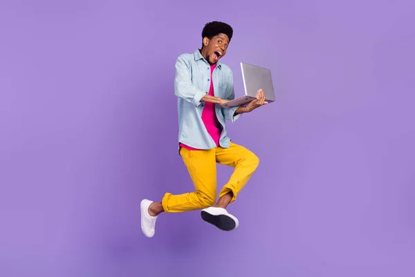 Foto do freelancer guy jump hold laptop digitação e-mail run desgaste azul camisa calças sapatos isolado cor roxa fundo — Fotografia de Stock