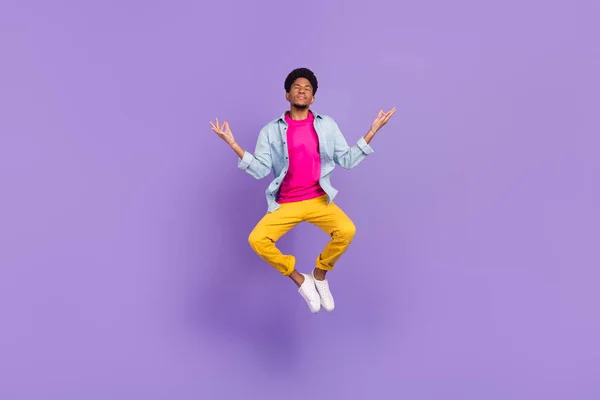 Foto de chico pacífico salto yoga práctica cerrar los ojos usar pantalones de camisa azul zapatos aislados color púrpura fondo —  Fotos de Stock