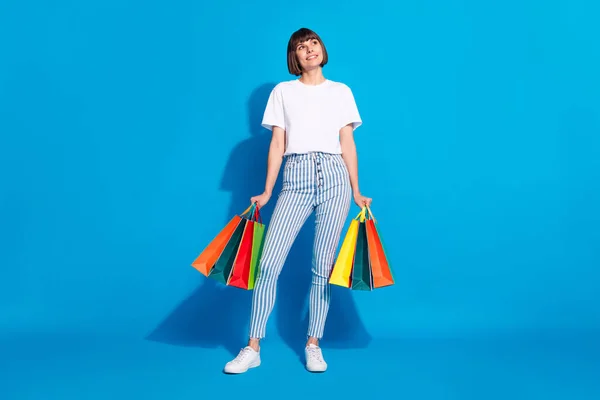 Pełna długość ciała rozmiar zdjęcia dziewczyna prowadzenie toreb po sprzedaży patrząc copyspace odizolowany jasnoniebieski kolor tło — Zdjęcie stockowe
