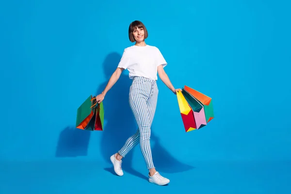 Ganzkörpergröße Foto Mädchen halten Taschen zu Fuß in Einkaufszentrum isoliert lebendige blaue Farbe Hintergrund — Stockfoto