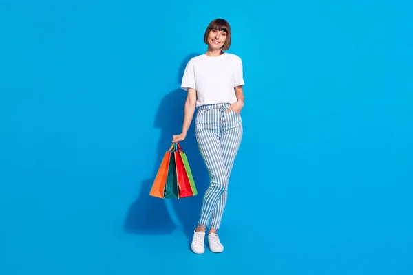Foto von entzückenden süßen jungen Dame tragen weißes Outfit lächelnd hält Schnäppchen isoliert blaue Farbe Hintergrund — Stockfoto
