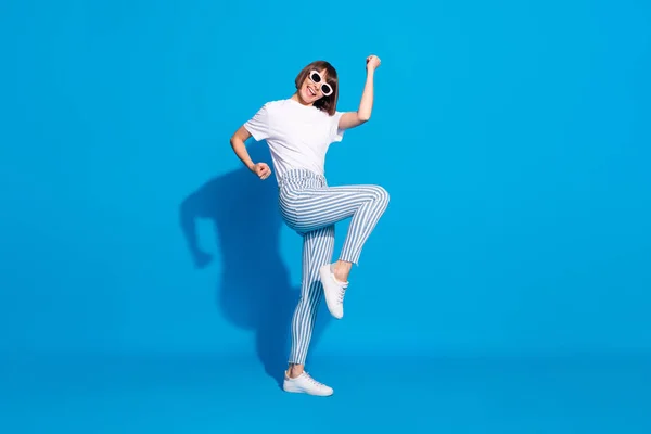 Full längd kropp storlek foto vårdslös flicka i solglas gest som vinnare isolerad ljus blå färg bakgrund — Stockfoto