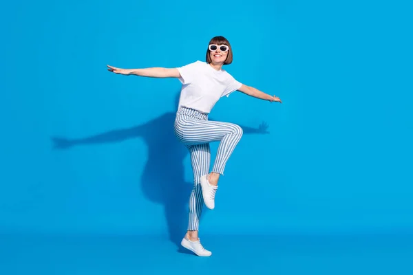 Longitud completa cuerpo tamaño foto descuidado chica en gafas de sol bailando en ropa casual aislado brillante color azul fondo — Foto de Stock