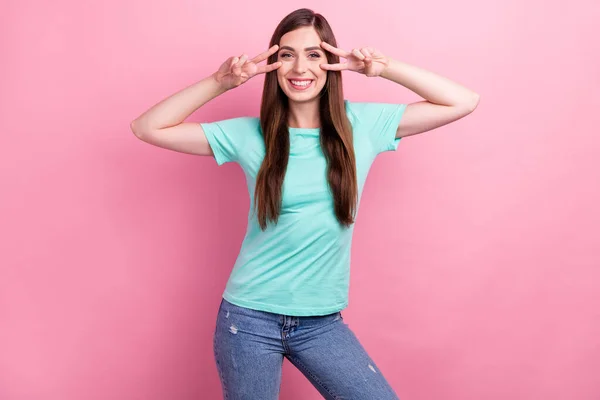 Foto de adorável encantadora jovem mulher vestida t-shirt turquesa mostrando v-sinal de cobertura olhos sorrindo isolado cor-de-rosa fundo — Fotografia de Stock