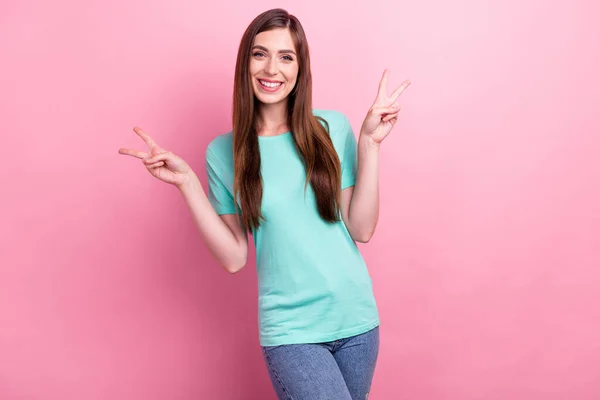 Фотография блестящей красивой молодой леди носить бирюзовую футболку улыбаясь показывая V-знаки изолированный розовый цвет фона — стоковое фото