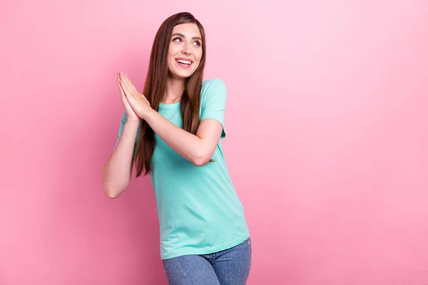 귀여운 한 젊은 여성 이 청록색 티셔츠를 입고 빈 공간을 보며 핑크 색 배경으로 웃고 있는 사진. — 스톡 사진