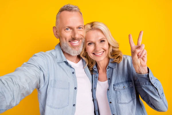 Foto de pensionista pareja esposa marido hacer selfie mostrar v-signo sonrisa disfrutar aislado en el fondo de color amarillo —  Fotos de Stock