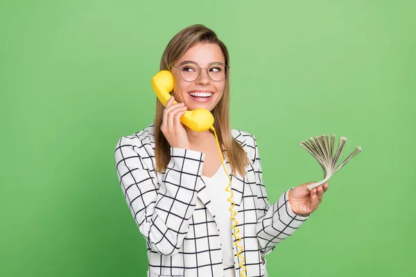 Portrait d'attrayant joyeux banquier fille branchée tenant dans les mains tas d'argent appelant la banque isolé sur fond de couleur vert vif — Photo