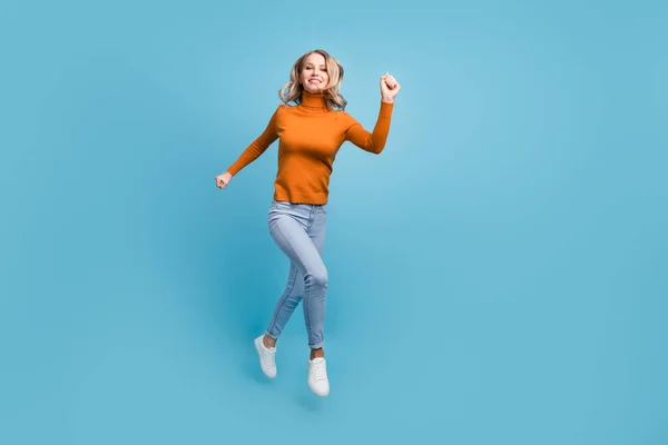 흥분 한 귀엽고 귀여운 젊은 여성 이 빠르게 고립된 푸른 색 배경을 따라 달리며 웃는 주황색 도르래를 입고 있는 사진 — 스톡 사진