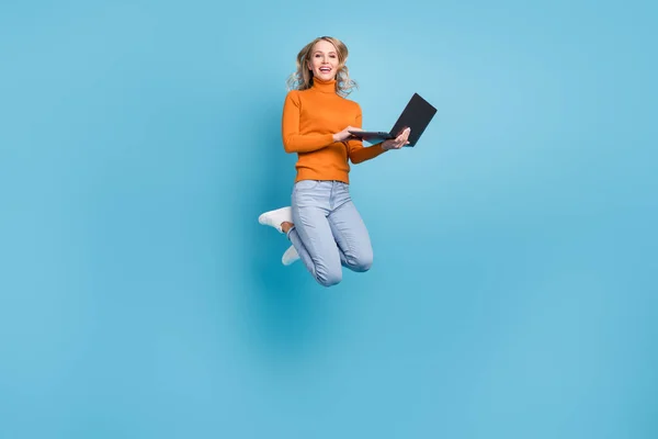 자신감 있는 젊은 아가씨가 주황색 스웨터를 입고 있는 사진 현대적 인 가젯 웃음 고립된 푸른 색상 배경 — 스톡 사진