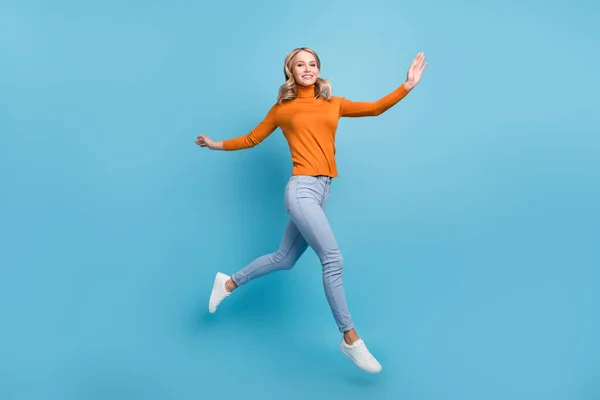 Foto de bastante adorable joven dama usar suéter naranja saltando alto sonriente aislado fondo de color azul —  Fotos de Stock