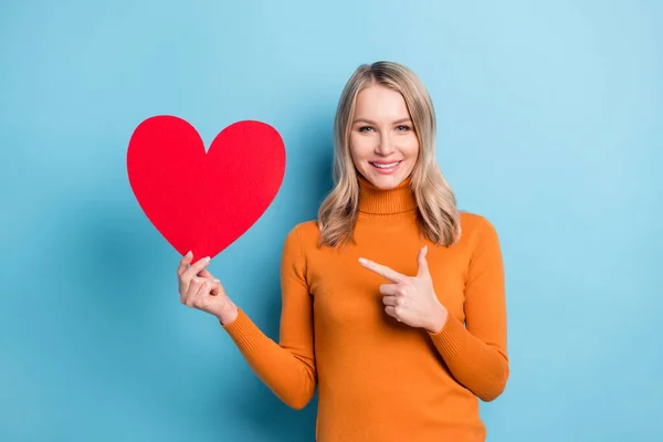 Fotografie okouzlující šťastná mladá žena bod prst červený papír srdce izolované na modrém pozadí — Stock fotografie