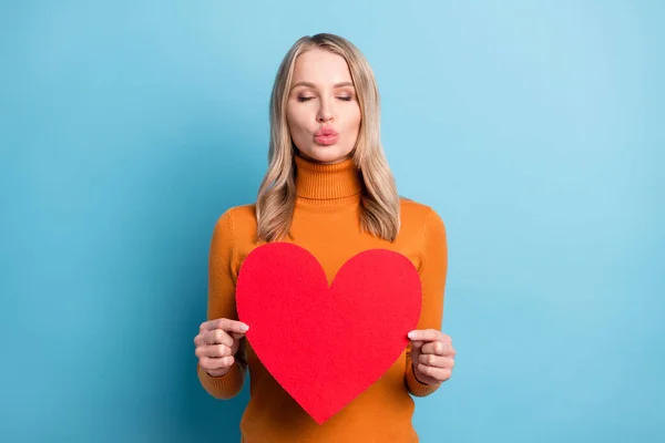 Fotografie flirtování okouzlující mladá hezká žena držet ruce velký červený papír srdce poslat vzduch polibek izolované na modrém pozadí — Stock fotografie