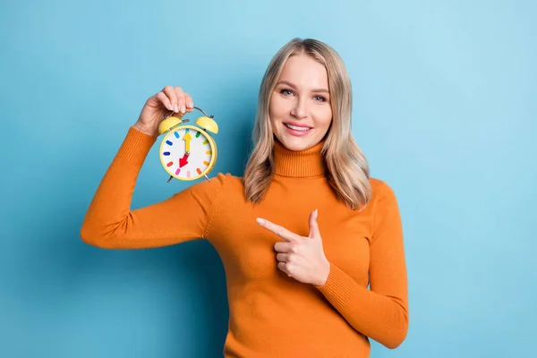 Foto de mujer joven positiva punta dedo alarma reloj gestión del tiempo aislado sobre fondo de color azul —  Fotos de Stock
