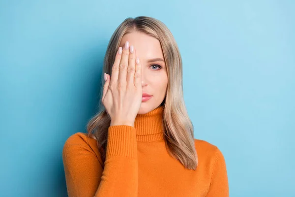 Foto van charmante lieve jonge vrouw gekleed oranje pullover arm dekking halve gezicht geïsoleerde blauwe kleur achtergrond — Stockfoto