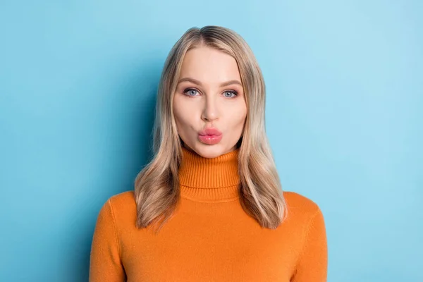 Фото милой флиртующей молодой женщины, одетой в оранжевый пуловер, посылающей вам поцелуй изолированный синий цвет фона — стоковое фото