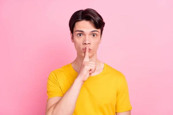 Foto de un joven serio y confiado usar camiseta amarilla dedo boca pidiendo no contar secretos aislados de color rosa de fondo — Foto de Stock