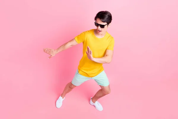 Foto di dolce funky giovane ragazzo vestito giallo t-shirt occhiali scuri ballare sorridente isolato colore rosa sfondo — Foto Stock