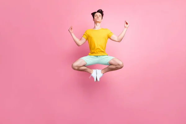 Foto av rolig fridfull ung man bära gul t-shirt hoppa hög praktiserande yoga isolerad rosa färg bakgrund — Stockfoto
