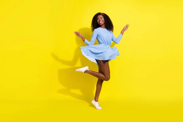 Comprimento total do corpo tamanho foto de menina dançando em azul pontilhado vestido olhando espaço vazio passar tempo livre isolado vívido cor amarela fundo — Fotografia de Stock