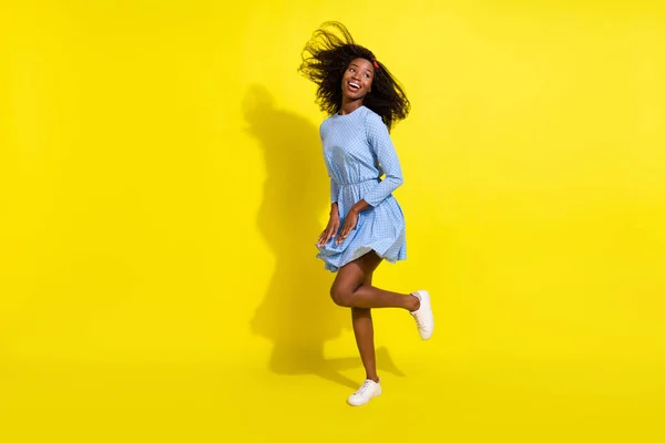 Tamanho total do corpo foto de menina dançando em vestido pontilhado azul olhando espaço vazio isolado no fundo de cor amarelo brilhante — Fotografia de Stock