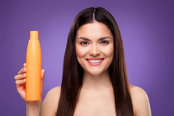 Porträt einer attraktiven, fröhlichen Frau, die eine Balsam-Flasche in der Hand hält, isoliert über einem hellen violetten Hintergrund — Stockfoto