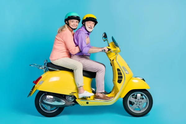 Foto de engraçado avó bonita avô motociclista usar capacetes sorrindo isolado azul cor de fundo — Fotografia de Stock