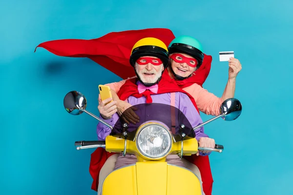 Porträt von zwei fröhlichen Senioren Rentner fahren Moped mit Karte kaufen Auftrag isoliert über hellblauen Farbhintergrund — Stockfoto