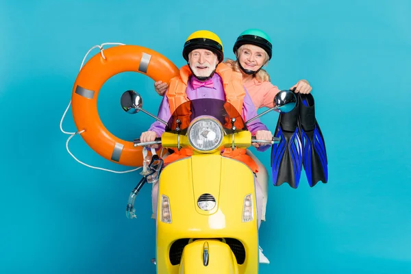 Gri saçlı yaşlı çiftin resmi evli çiftler tatil bisikletçisi lastik şişirilebilir daire miğferi var mavi arka planda izole edilmiş — Stok fotoğraf