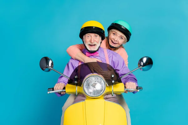 Foto van positieve grijze haren paar dragen helm rijden motorfiets knuffel geïsoleerd op pastel blauwe kleur achtergrond — Stockfoto