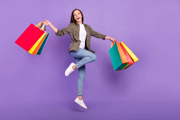Tam boy vücut ölçülerinde fotoğraf çeken bir kadın alışveriş merkezinde çantaları mor renkli arka planda tutarken mutlu oluyor. — Stok fotoğraf