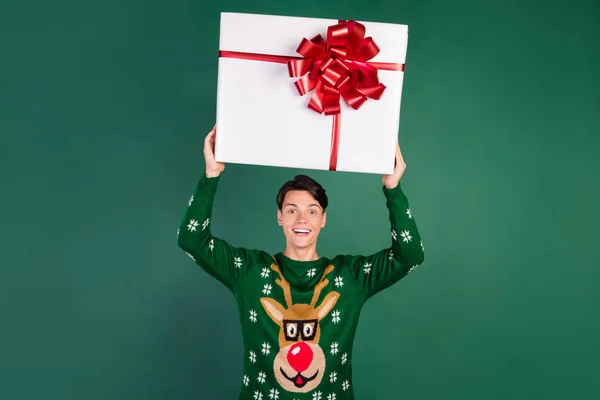 Foto von erstaunt überrascht Kerl halten große Geschenkbox heben Hände tragen Hirsch Ornament Pullover isoliert grüne Farbe Hintergrund — Stockfoto