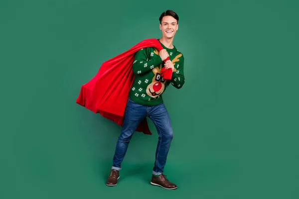 Foto von starken fröhlichen Kerl tragen großen Sack präsentiert tragen Hirsch Ornament Pullover isoliert grüne Farbe Hintergrund — Stockfoto